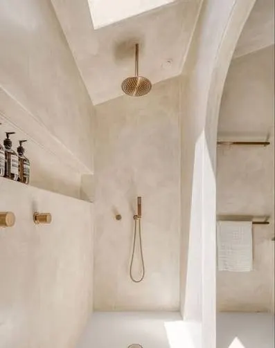 Bathroom with limewashed walls, a skylight and brushed brass shower rose and tapware