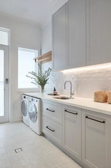 Long galley laundry with grey shaker cabinetry, LED strip lighting, washer and dryer and a garden door