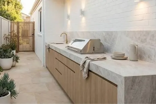 Outdoor kitchen in a Sydney courtyard with a thick stone benchtop, built in barbecue and timber cabinetry