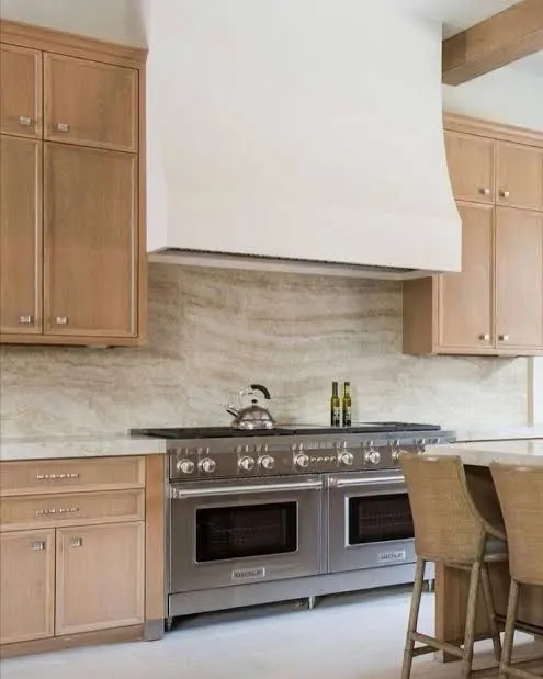 Warm timber kitchen with a rendered plaster rangehood, natural stone splashback and freestanding oven