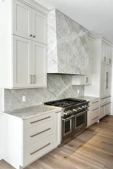 White shaker style kitchen with a marble clad rangehood, marble splashback and freestanding gas cooker